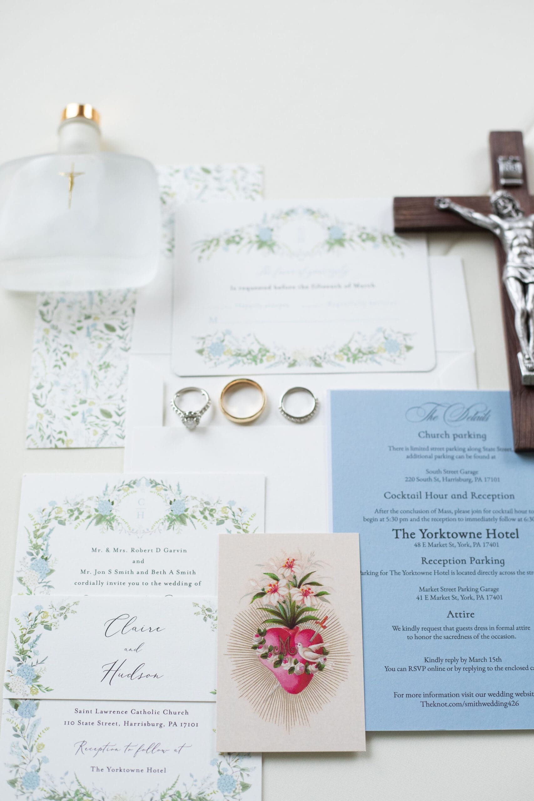 Wedding Flatly of a Catholic bride's details featuring a Crucifix, invitation suite, rings, and a holy card. 