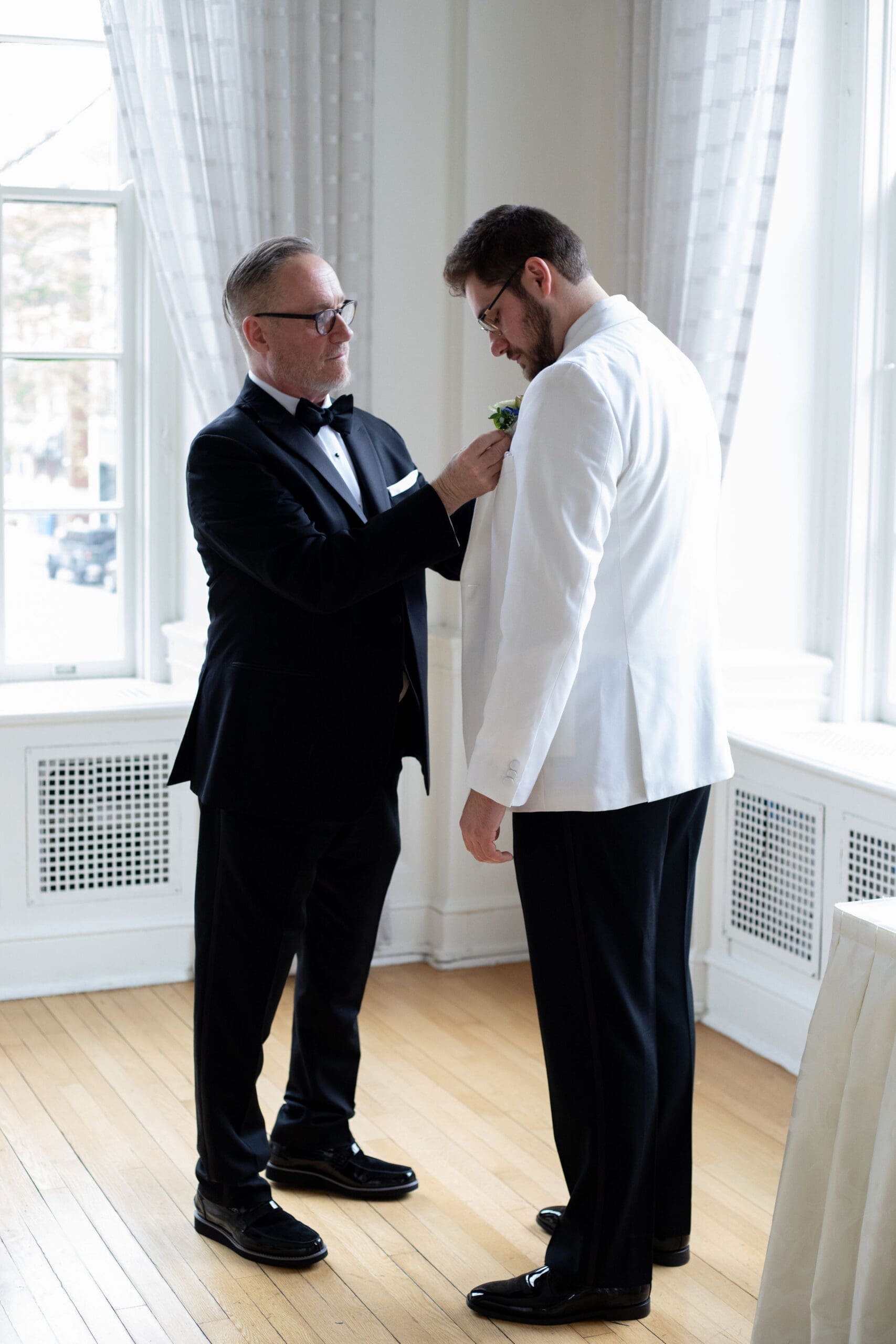 Father of the groom pins Boutonnière on the groom before the wedding ceremony 