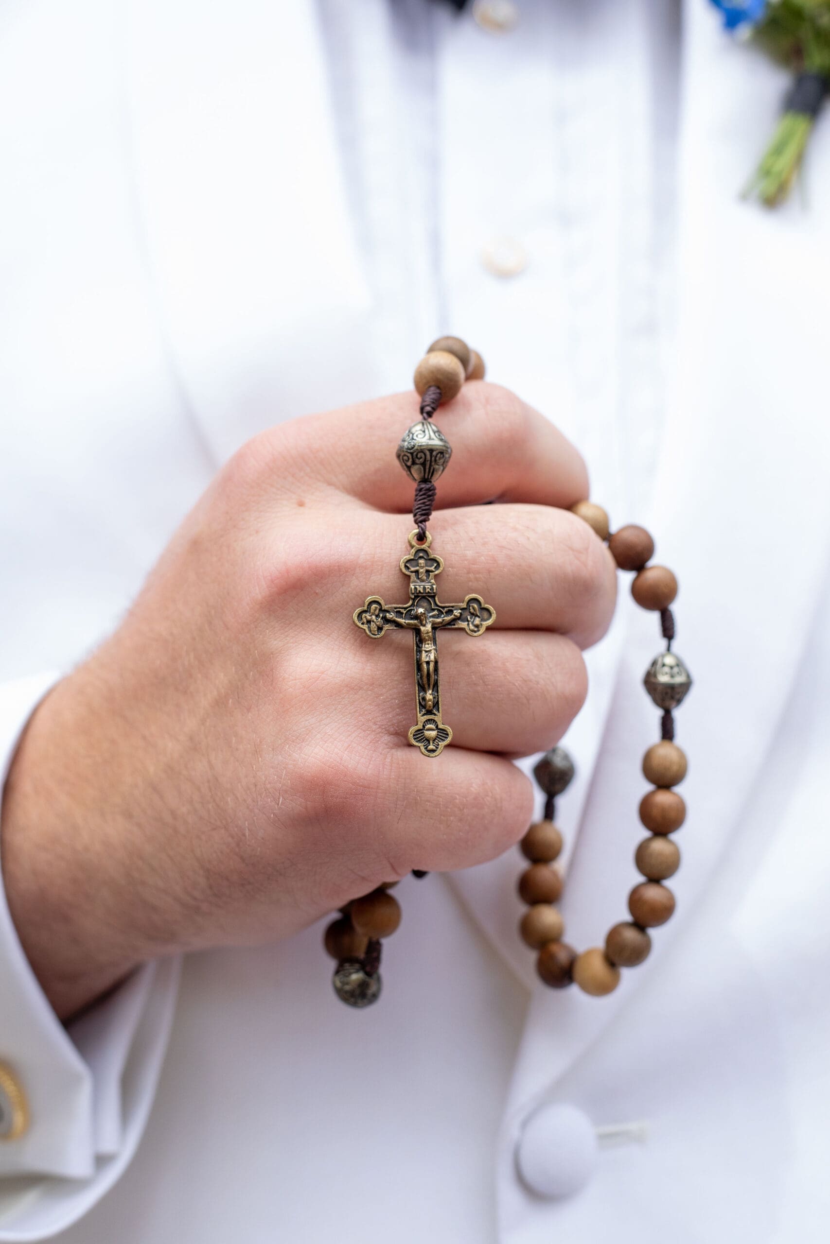 Groom prays a rosary before his Catholic wedding Mass. Featuring the Crucifix 