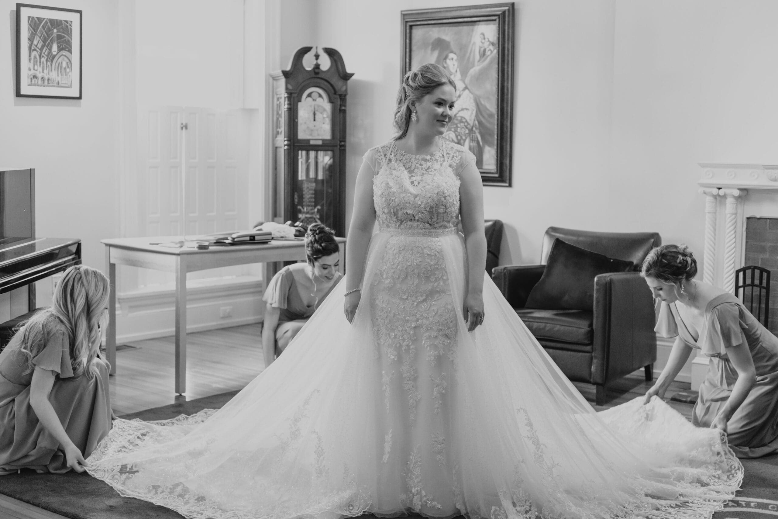 Bridesmaid fluff the bride's dress before she walks down the aisle of her Catholic wedding ceremony 