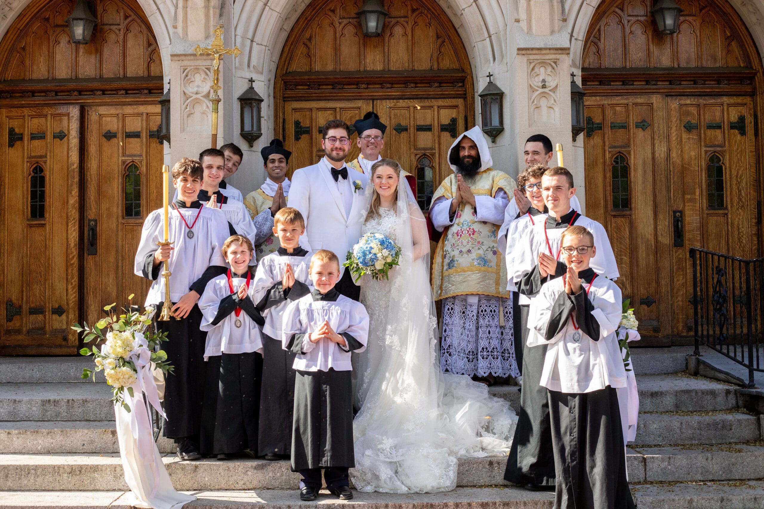 Bride and groom pictured outside of their wedding with the Priest and altar servers 