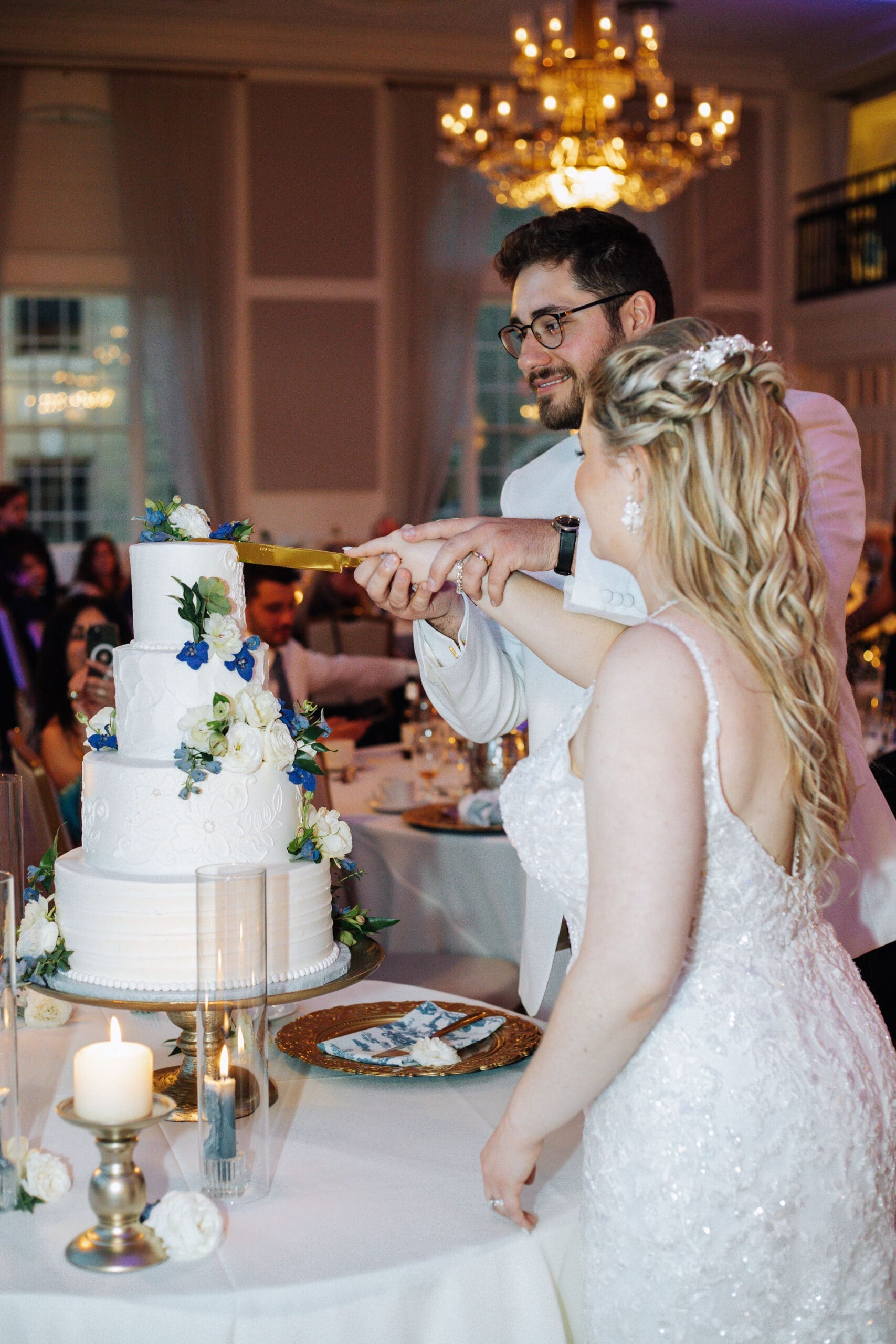 Bride and groom cut their beautiful vanilla wedding cake during their wedding reception 