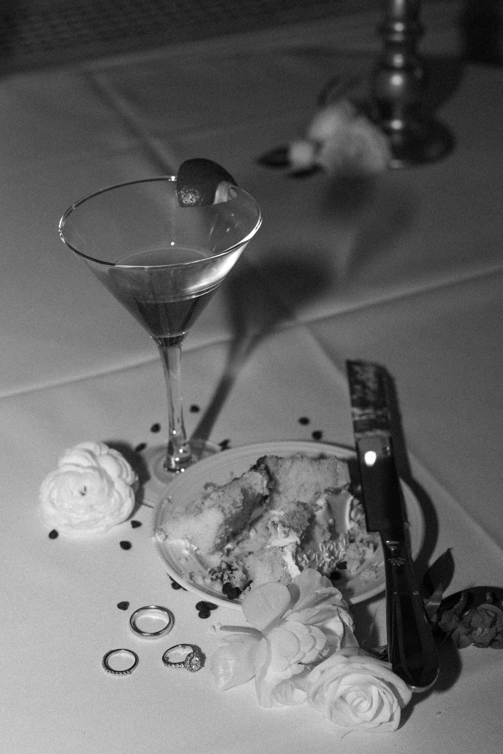 Late night wedding detail featuring the Bride's drink, their cake, and wedding bands 