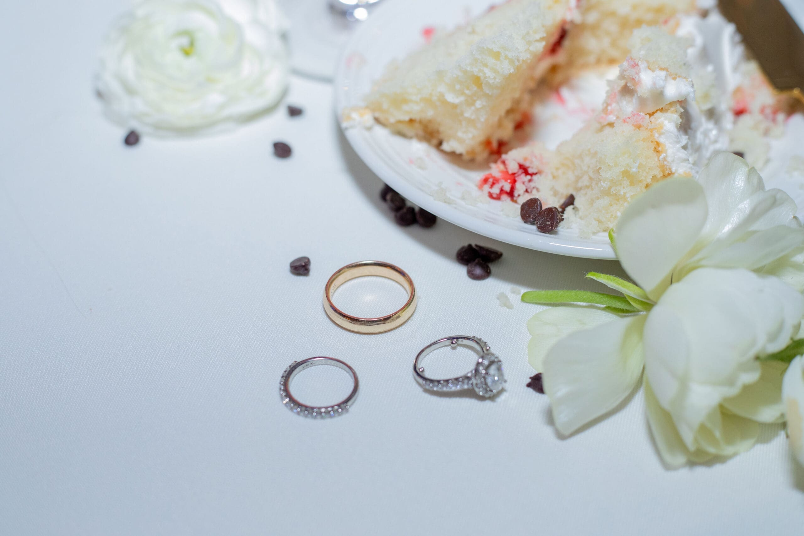 Late night wedding details featuring wedding cake and rings 